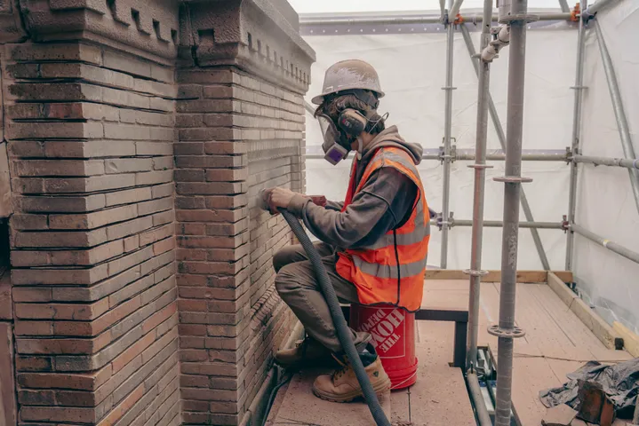 Masonry worker restoring a brick facade from scaffolding
