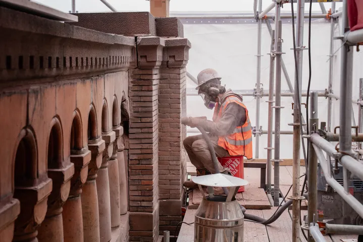 Worker repairing decorative stonework on a building facade