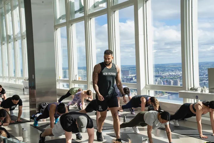 Fitness instructor leading a class beside tall windows