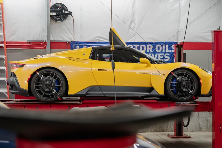 Yellow sports car raised on a workshop lift