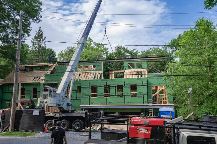 Crane lifting materials over a residential construction site